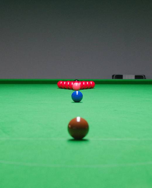 Ein Snookertisch mit vollständig aufgebautem Dreieck roter Kugeln hinten und farbigen Kugeln in ihrer Startposition entlang der Mittelachse.